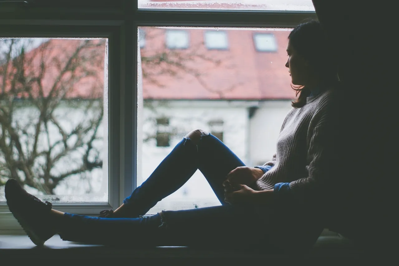 Person sitting by a window looking out — the psychological effects of social media and the digital experience
