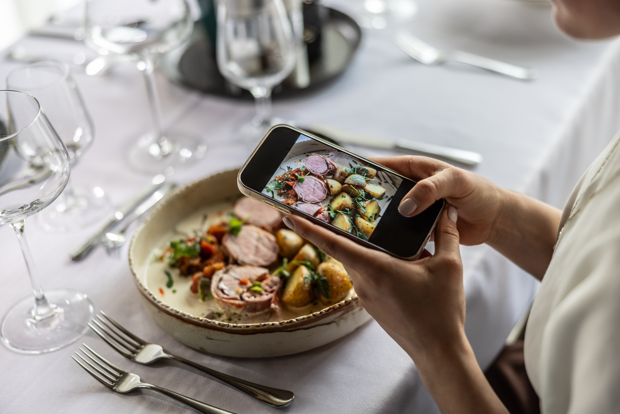 Diner photographing a plated dish with a smartphone — social media strategy for restaurants and hospitality brands