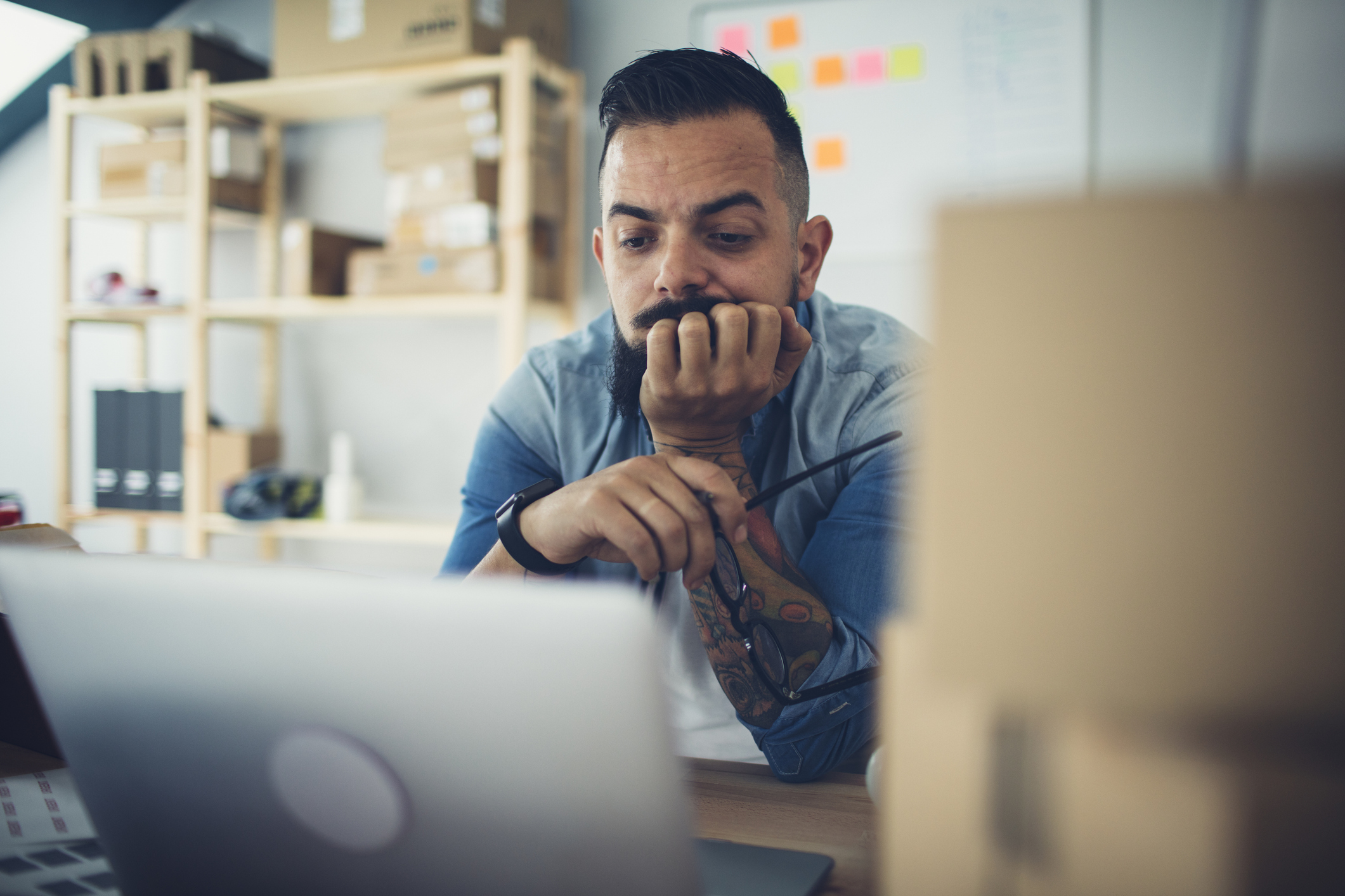Small business owner looking stressed at a laptop — 5 signs your brand needs a social media manager